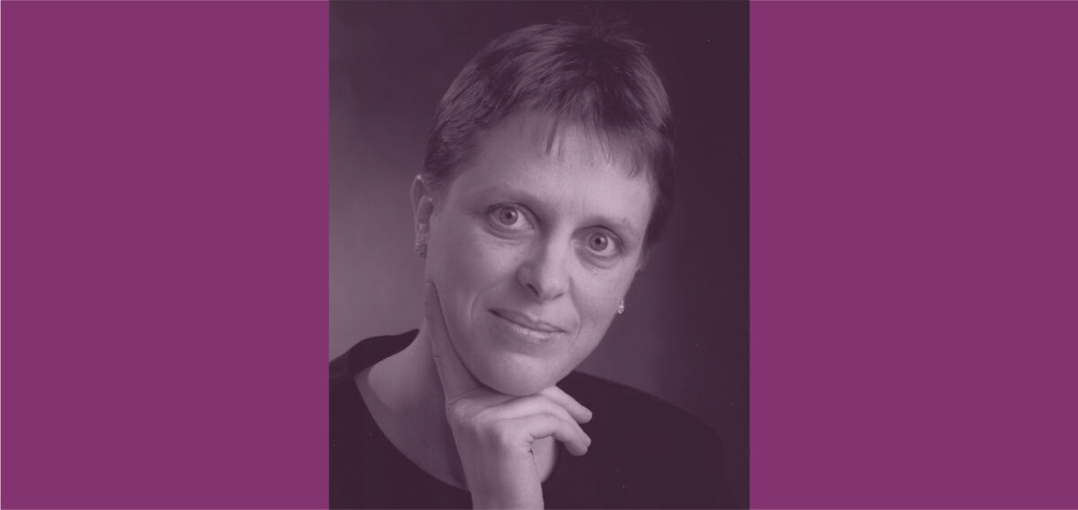 Photo of Diana Brebner against a purple background. Diana is a white woman with short hair, and her hand is tucked under her chin.